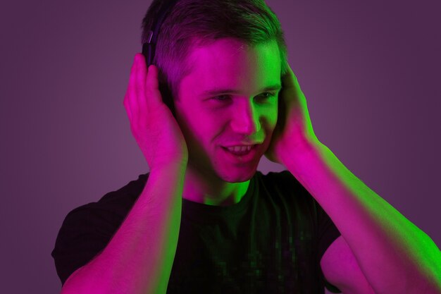 Man's portrait isolated on purple studio wall in neon light