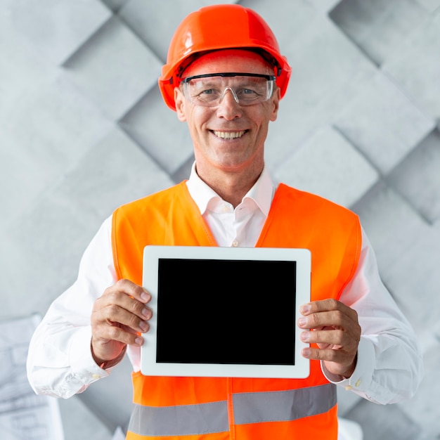 Free photo man in safety equipment showing a tablet mock-up