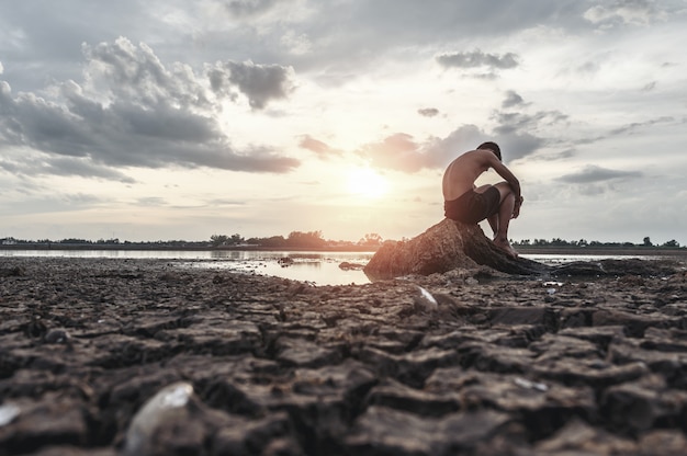 A man sat bent his knees on the base of the tree where the floor was dry and hands placed on the head.