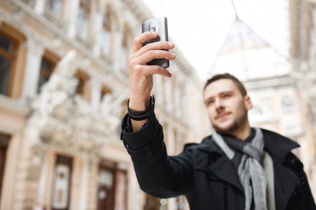 Free photo man shooting magnificent architecture on phone while walking around city.