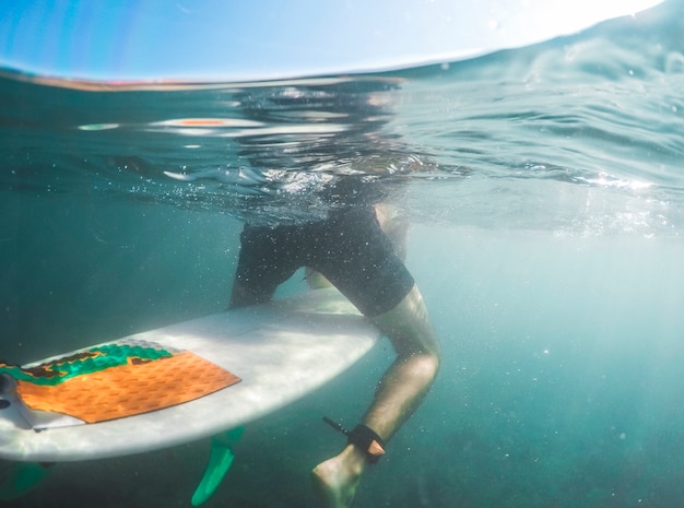 Free Photo man in shorts sitting on surfboard in blue water