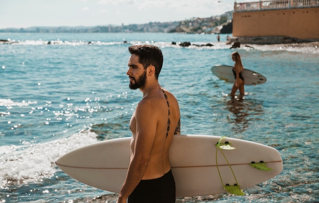 Man in shorts standing with surfboard in sea