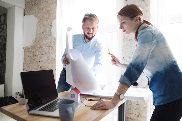 Man showing blueprint to his female colleagues at workplace