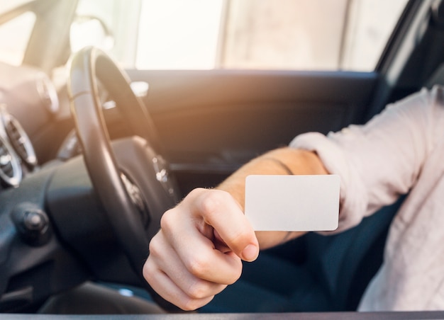 Free photo man showing business card in car