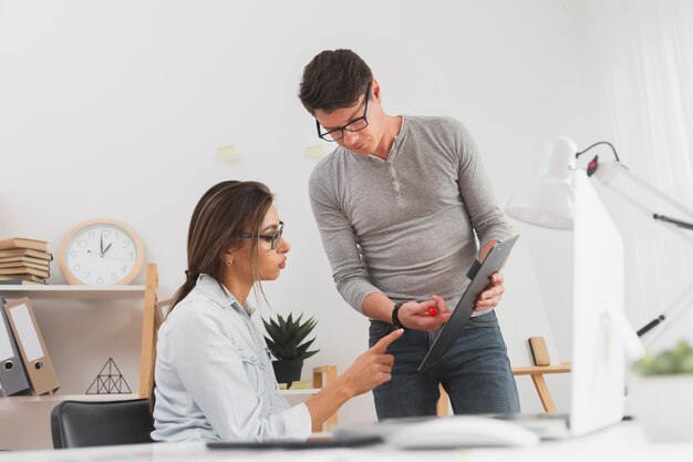 Man showing data from a clipboard to a business woman