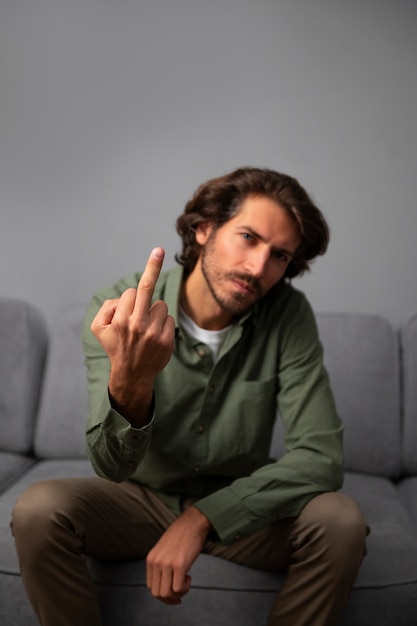 Man showing middle finger while sitting on the sofa