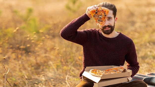 Free photo man showing a slice of pizza with copy space