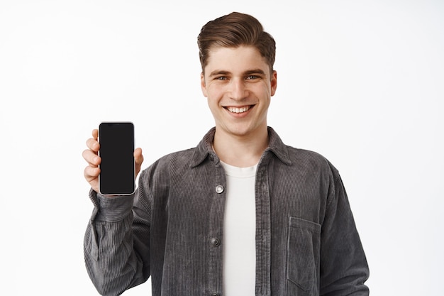  man shows smartphone screen, interface of application, recommending app, standing on white