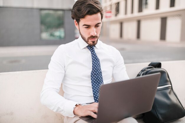 Man sitting on bench using laptop