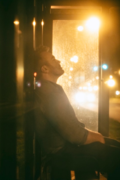 Man sitting at the bus station at night in the city