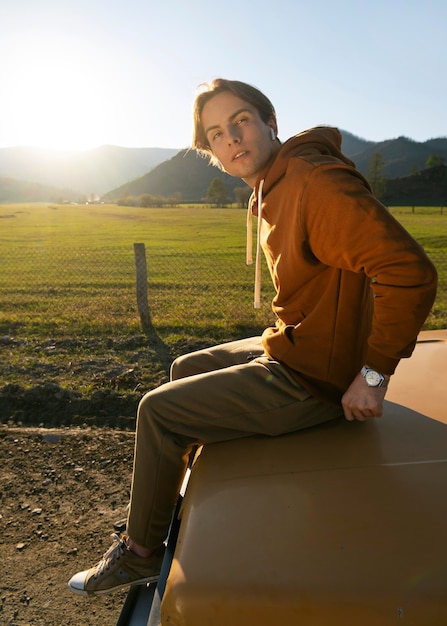 Free photo man sitting on car full shot