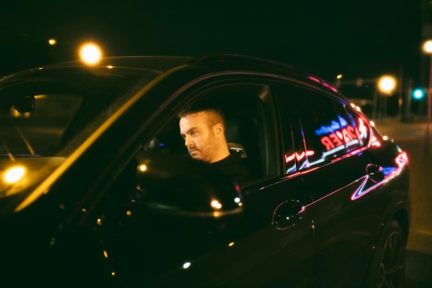 Free photo man sitting in the car at night