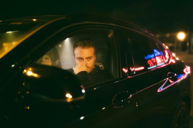 Free photo man sitting in the car at night