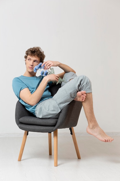 Free photo man sitting in chair and holding flowers