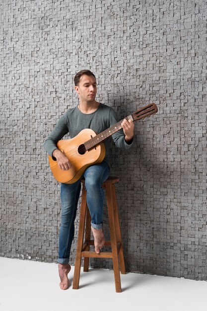 Man sitting on chair playing the classical guitar