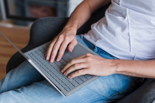 Free photo man sitting on chair and typing on laptop