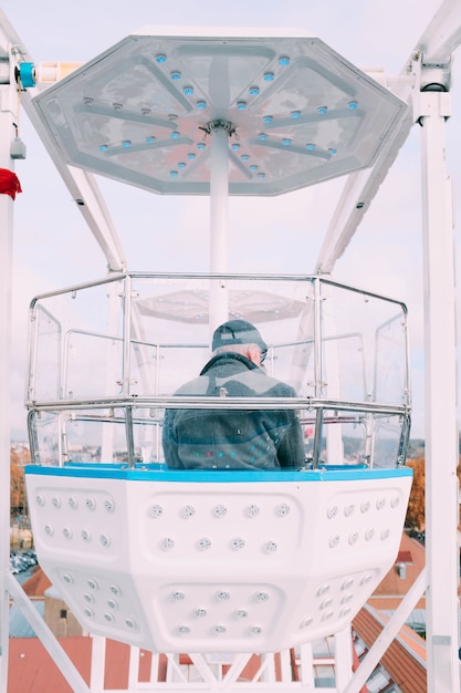 Free Photo man sitting in a ferris wheel carousel cabin during a ride