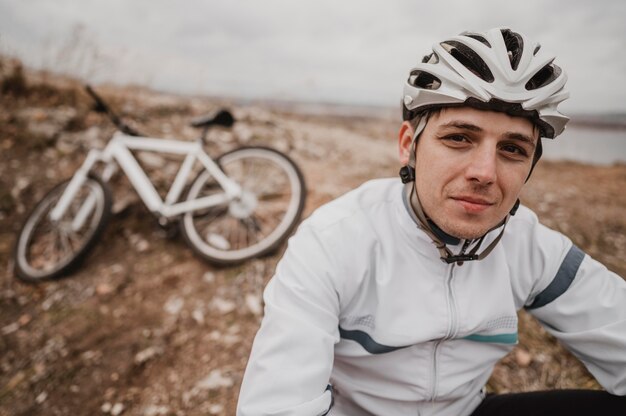 Free photo man sitting on the grass next to his mountain bike