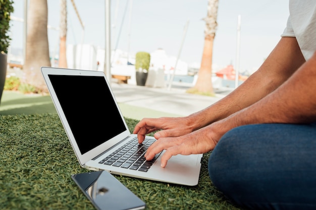 Free Photo man sitting on grass with portable devices