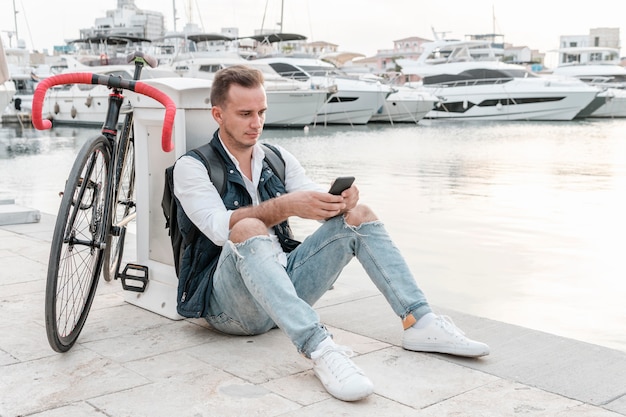 Man sitting next to his bike and playing on the phone