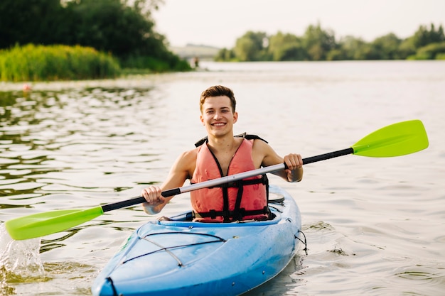 Free Photo man sitting in kayak using paddle on lake