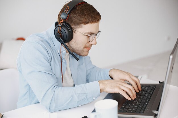 Man sitting in living room at home. Guy enjoying studying using laptop and headset.