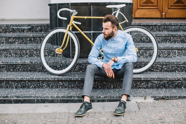 Free Photo man sitting on stairs near building