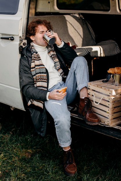 Free photo man sitting in a van drinking his coffee