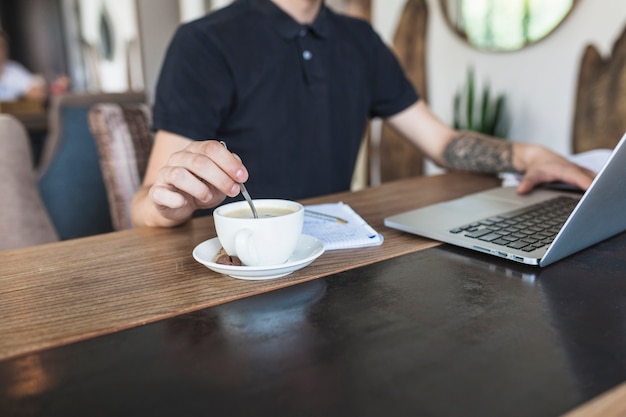 Free photo man sitting with laptop and coffee at table