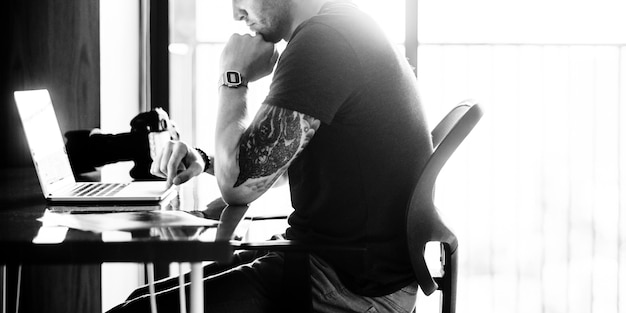 Man sitting working on laptop grayscale