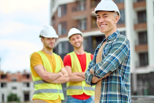 Man smiling at camera and workers behind