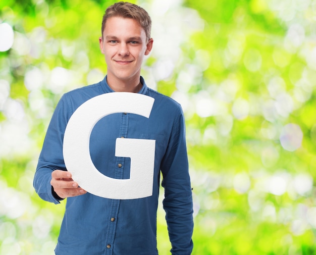 Free Photo man smiling holding the letter "g"