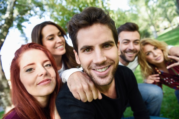 Man smiling taking a self photo of him and his friends with trees in the background