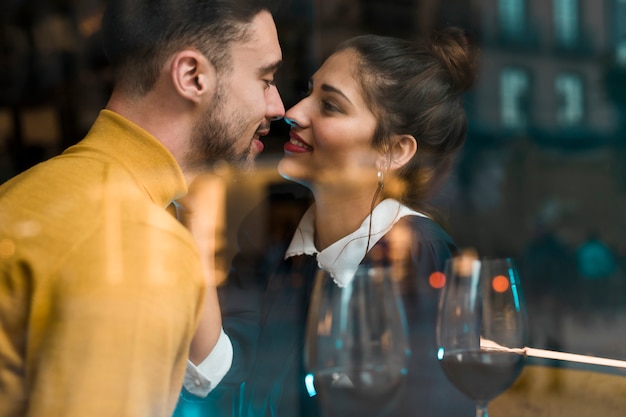 Free photo man and smiling woman near glasses of wine in restaurant near window