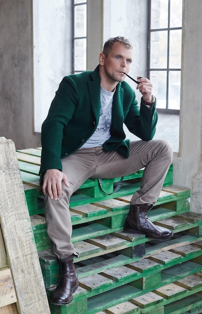 Free photo man smokes pipe and posing in a room of a warehouse.