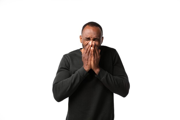 Man sneezing on white wall