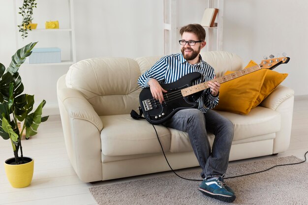 Man on sofa at home playing electric guitar