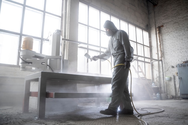 Man spraying powder paint  full shot