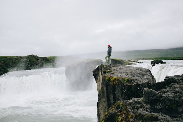 Man stand over cliff of epic watefall