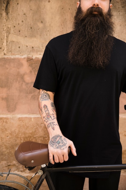 Man standing against wall with his hand on bicycle seat