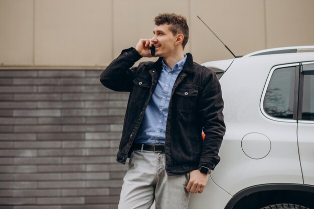 Man standing by his car and talking on the phone