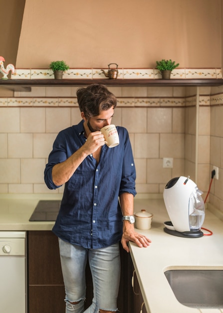 Man standing in kitchen drinking coffee