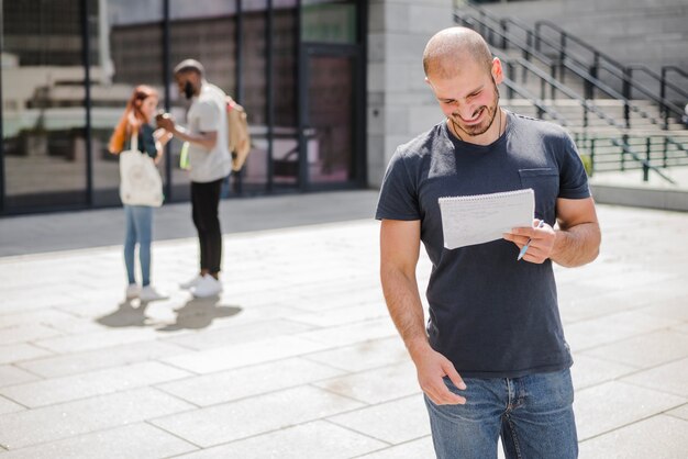 Man standing outside holding notepad smiling