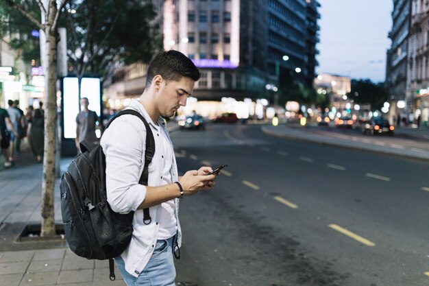 Man standing on roadside looking at mobile phone screen