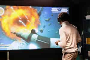 Free photo man standing up in front of ultrawide screen playing videogame using controller