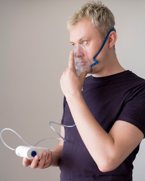 Man standing and using an oxygen mask