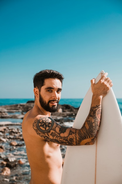 Man standing with white surfboard on beach