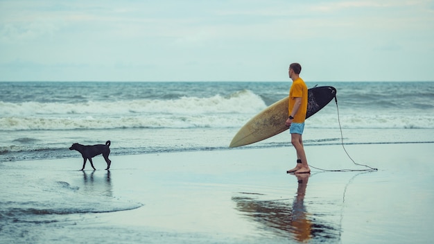 Free photo a man stands on the beach with a surfboard.