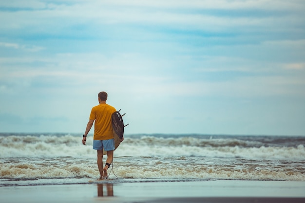 A man stands on the beach with a surfboard. 