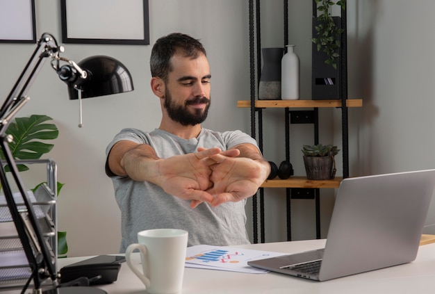 Free Photo man stretching his arms while working from home